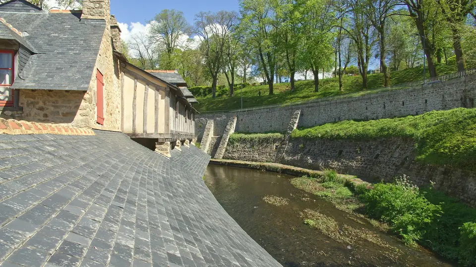 Toits d’ardoise au bord d’une rivière, entre murs de pierre et jardins