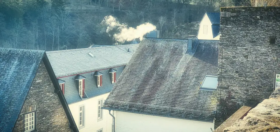 Souches de cheminée qui fument sur des toits d’ardoise