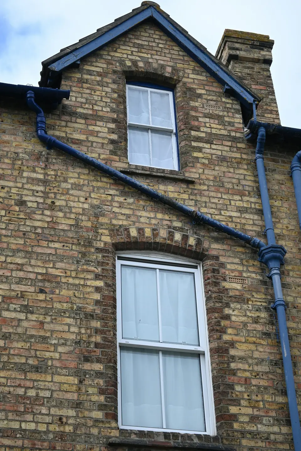 Lucarne et descentes d’eau sur une maison en brique au toit d’ardoise