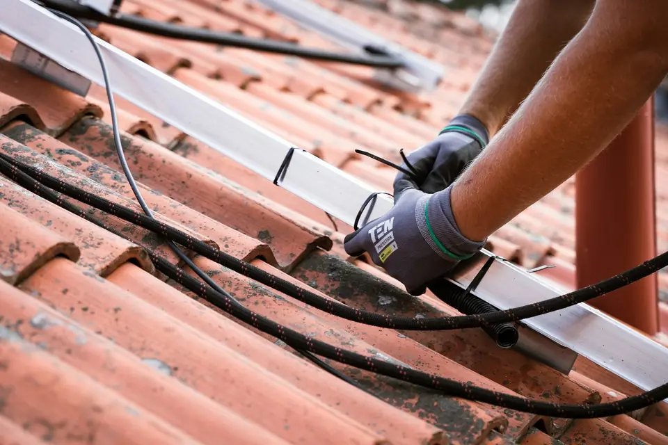 Couvreur aux gants de travail sur une toiture en tuiles