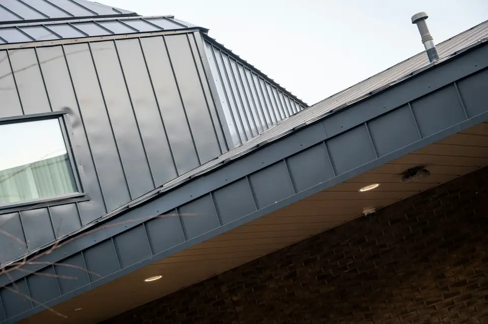 Bord de toit habillé de métal au-dessus d’une façade en brique